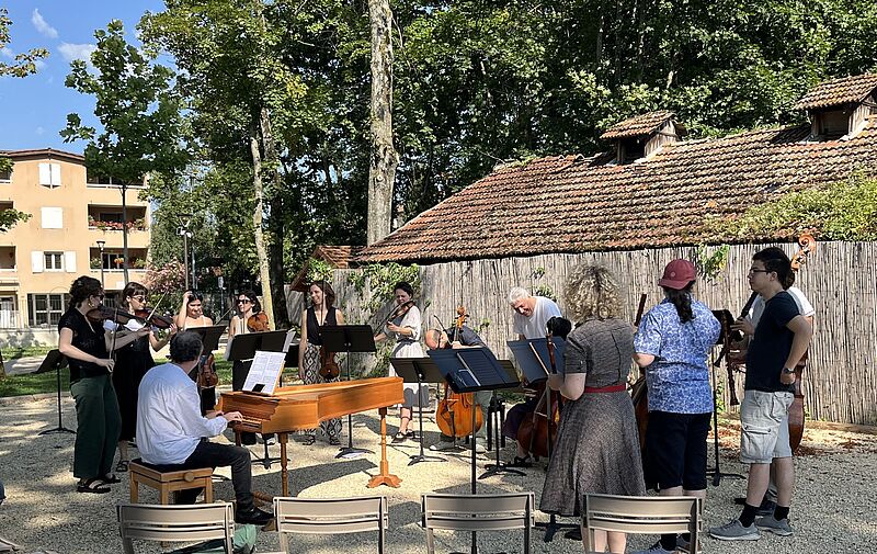 Musiker stehen um ein Cembalo im sonnigen Park
