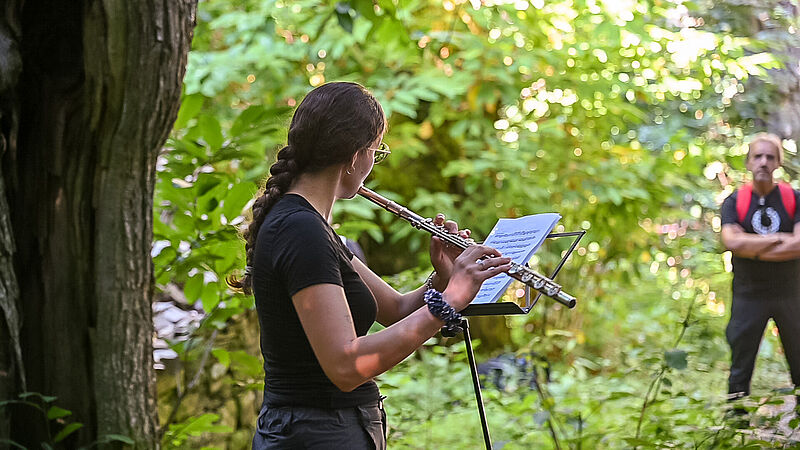 Frau spielt Querflöte im Wald
