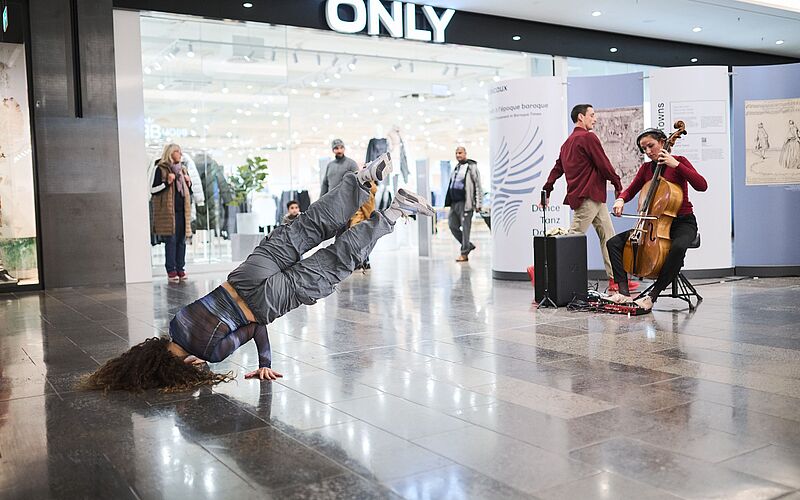 HipHop-Tänzerin macht einen schrägen Kopfstand vor einem Laden.