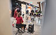 Cellistin von hinten, dahinter zwei Tänzer